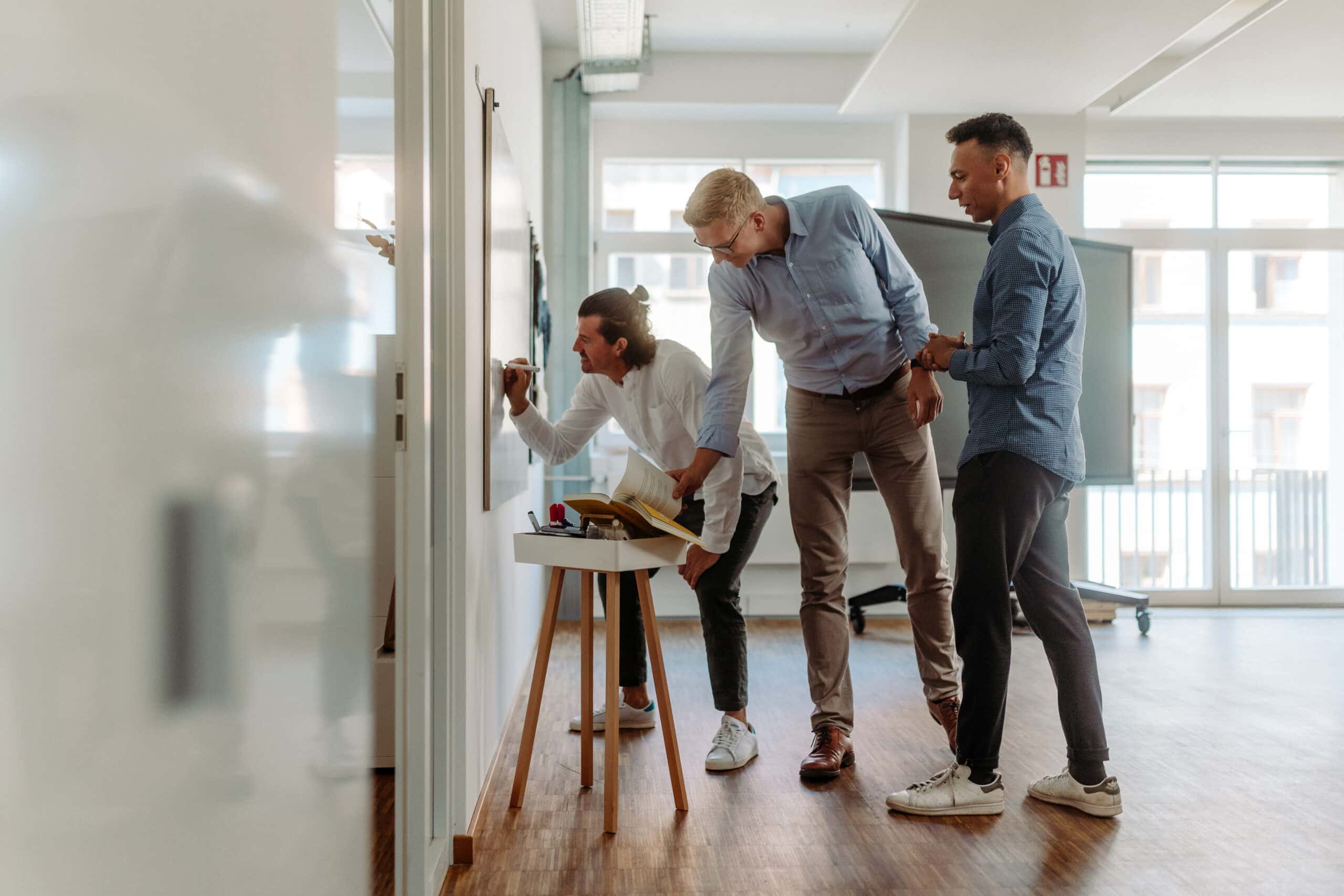 Teilnehmer des kreativen Technologie-Workshops bei ATHEM erarbeiten gemeinsam neue Ideen an einem Whiteboard.