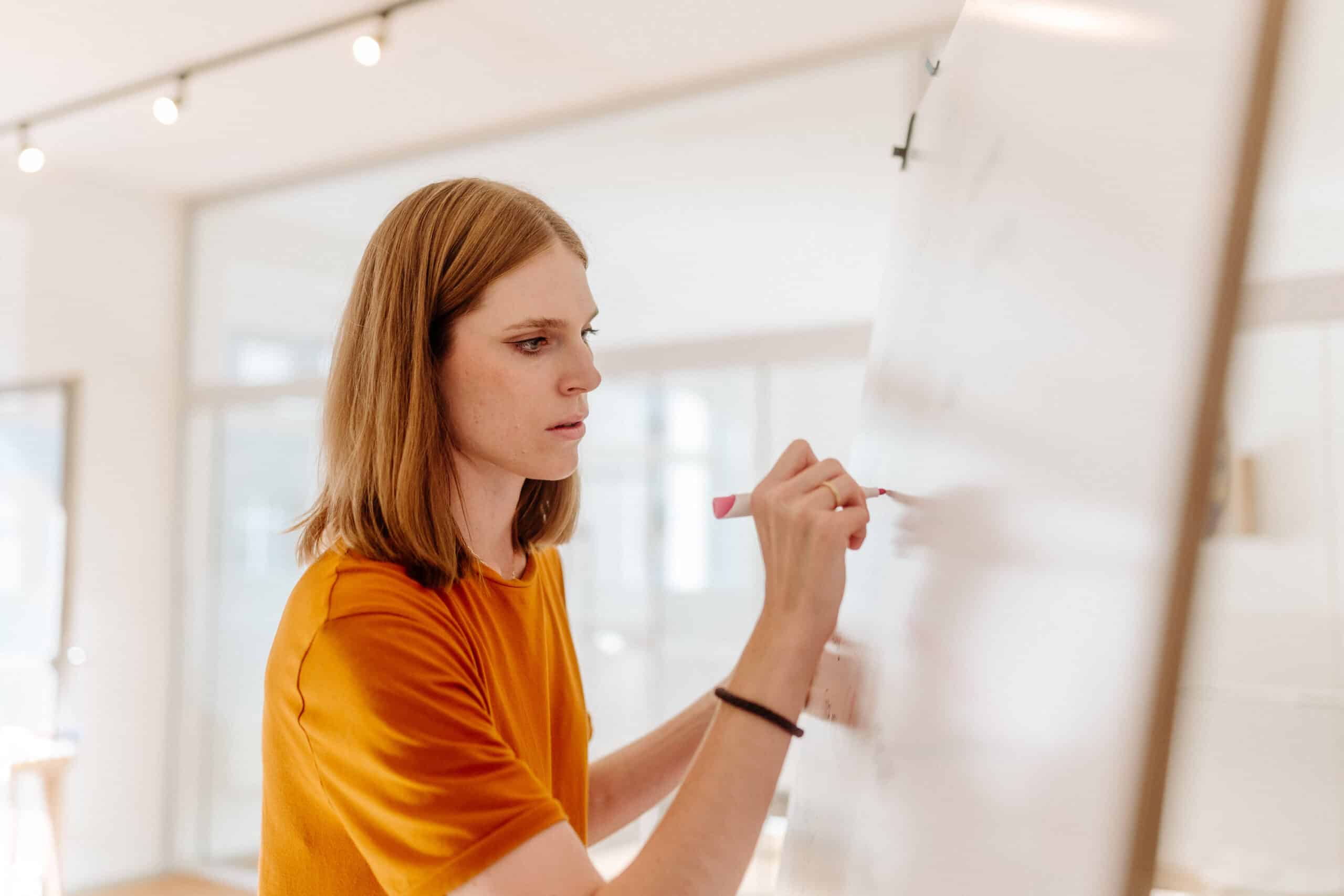 Ein Workshop-Teilnehmerin schreibt engagiert und konzentriert auf ein Whiteboard.