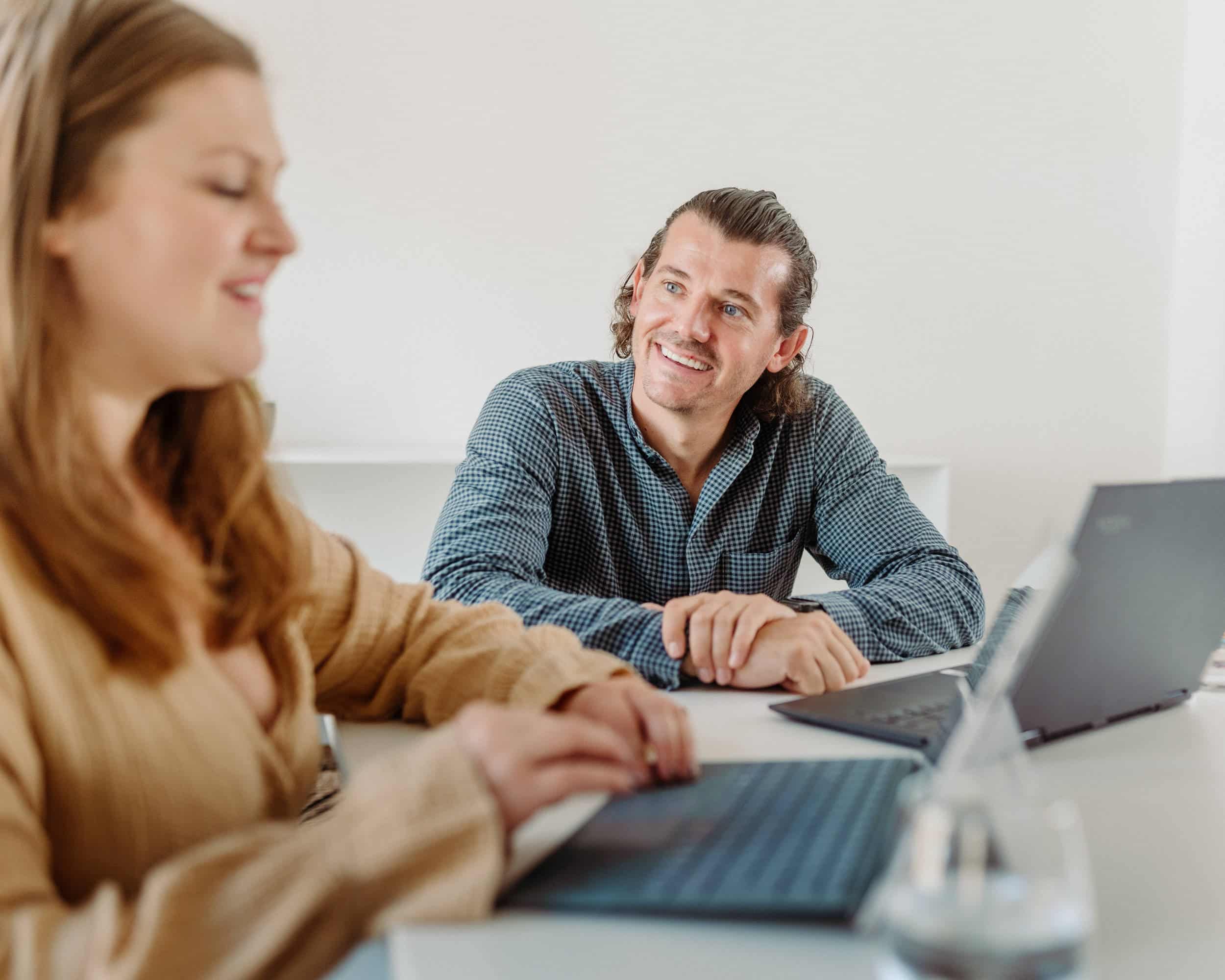 Toni und Karin tauschen sich engagiert am Meeting-Tisch aus.